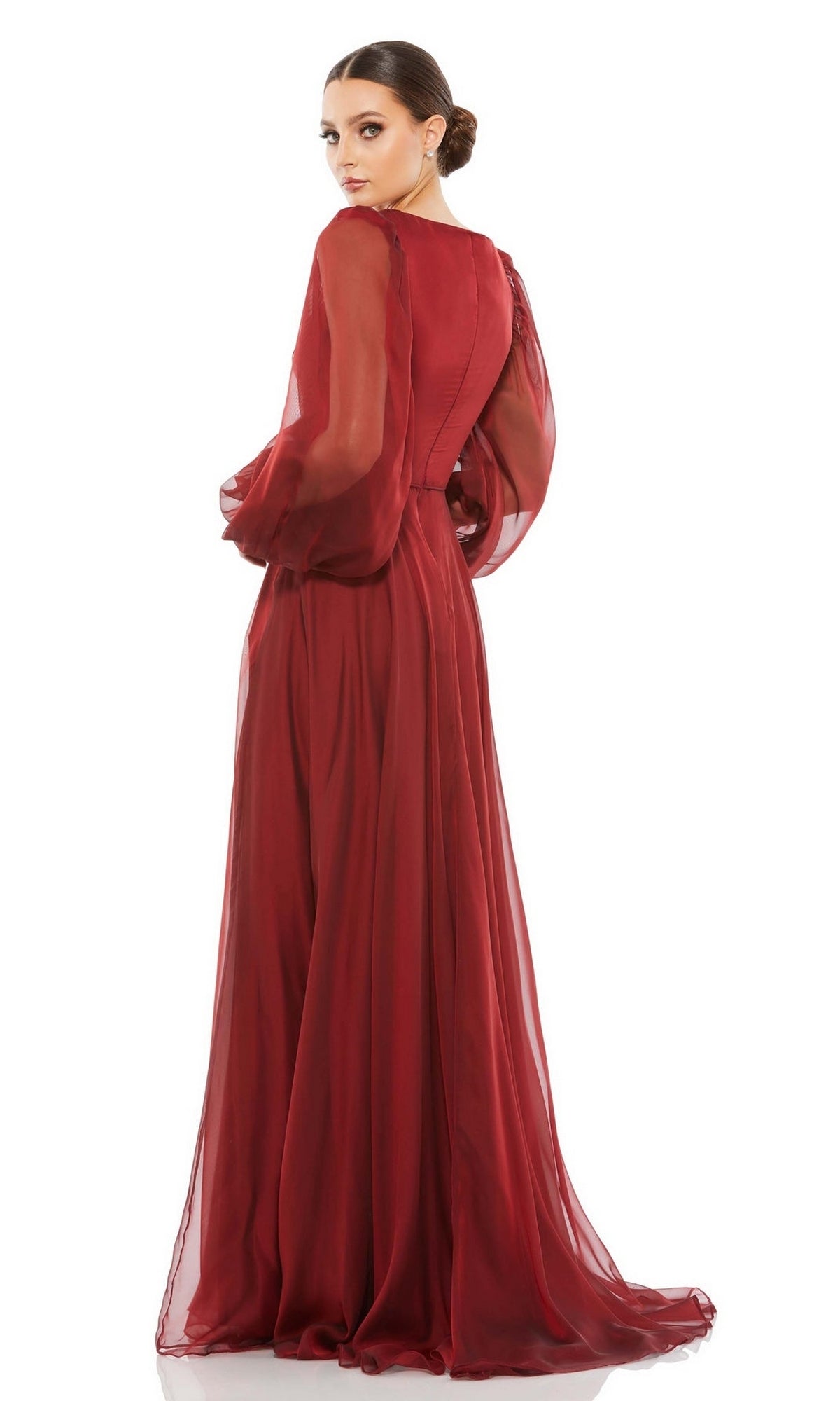 Model wears the Mac Duggal 67873 long sleeve red formal gown, standing with her back to the camera and glancing over her shoulder against a white background.